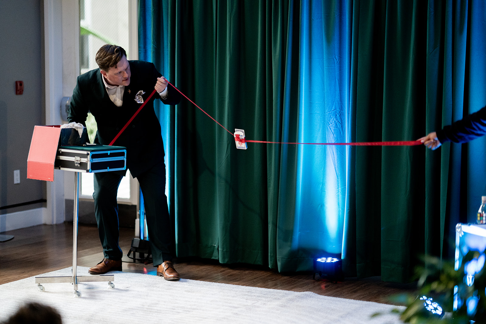 White Rabbit private magic show — emerald curtains and cinematic uplighting at a luxury corporate event